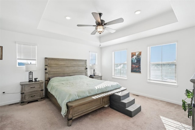 carpeted bedroom with ceiling fan and a tray ceiling