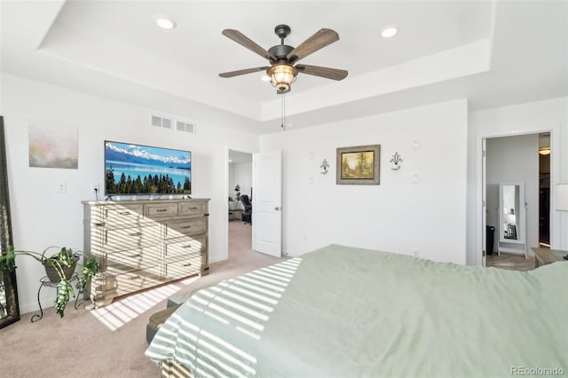 bedroom featuring a raised ceiling, light colored carpet, and ceiling fan