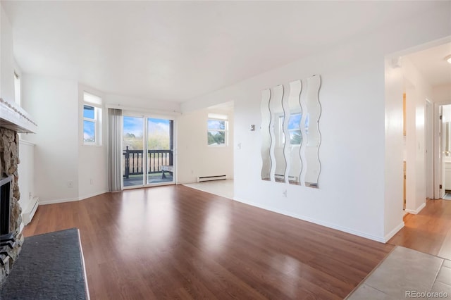 unfurnished living room with light hardwood / wood-style flooring, a baseboard radiator, and a fireplace