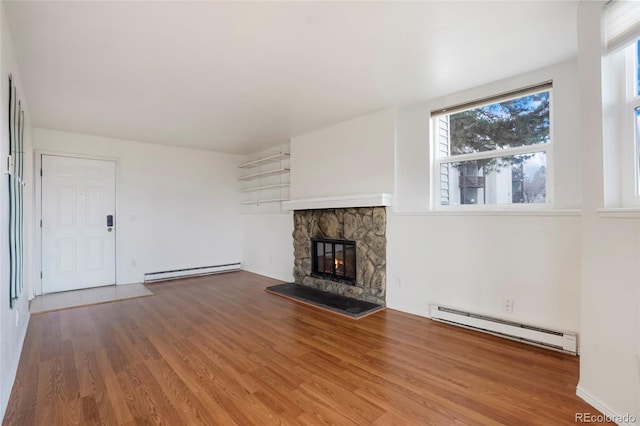 unfurnished living room featuring a baseboard heating unit, a fireplace, and hardwood / wood-style flooring