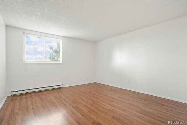 empty room featuring a textured ceiling, baseboard heating, and light hardwood / wood-style flooring