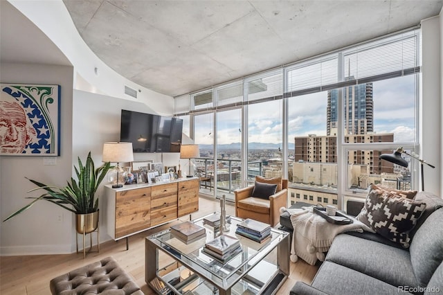 living room with floor to ceiling windows, light wood-style floors, baseboards, and visible vents