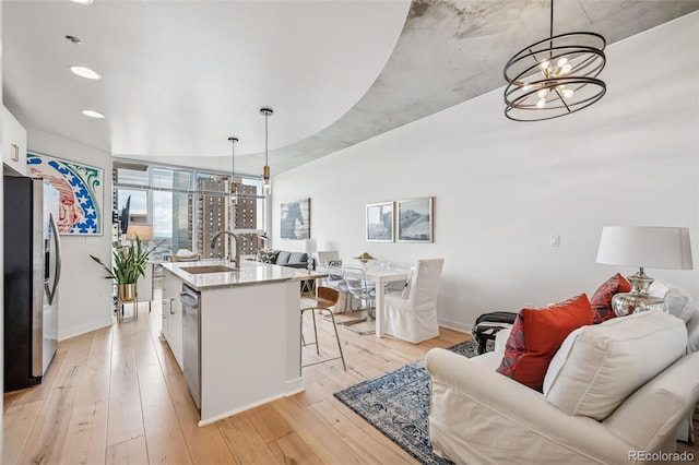 kitchen featuring stainless steel appliances, light wood finished floors, a kitchen bar, and a sink