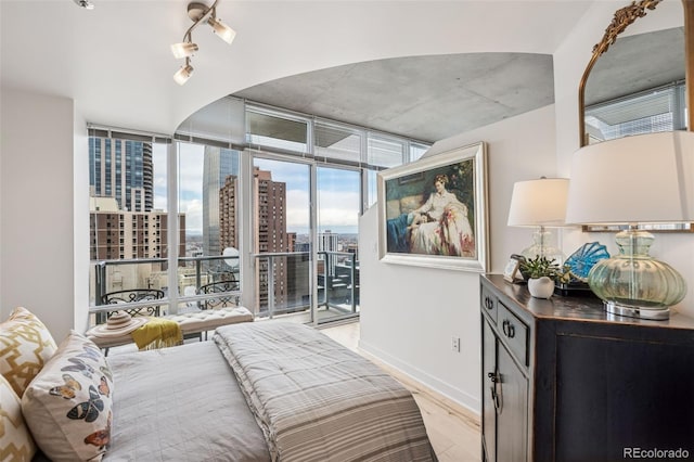 bedroom featuring a city view, expansive windows, access to outside, baseboards, and light wood-style floors