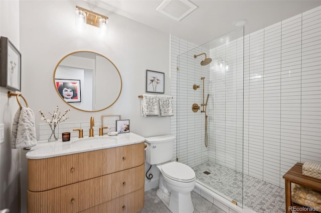 bathroom featuring a tile shower, vanity, tile patterned flooring, visible vents, and toilet