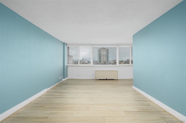 1196 N Grant St Unit 705, Denver, CO 80203 - empty room featuring radiator, wood finished floors, and baseboards