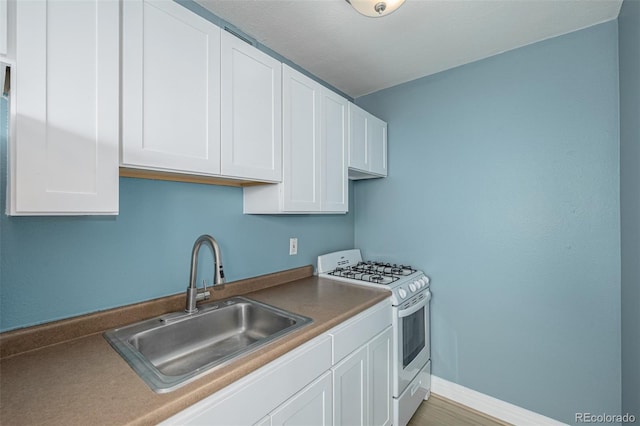 1196 N Grant St Unit 705, Denver, CO 80203 - kitchen featuring white range with gas cooktop, a sink, white cabinetry, and baseboards
