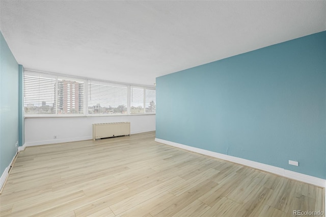 1196 N Grant St Unit 705, Denver, CO 80203 - unfurnished room with radiator heating unit, healthy amount of natural light, wood finished floors, and baseboards