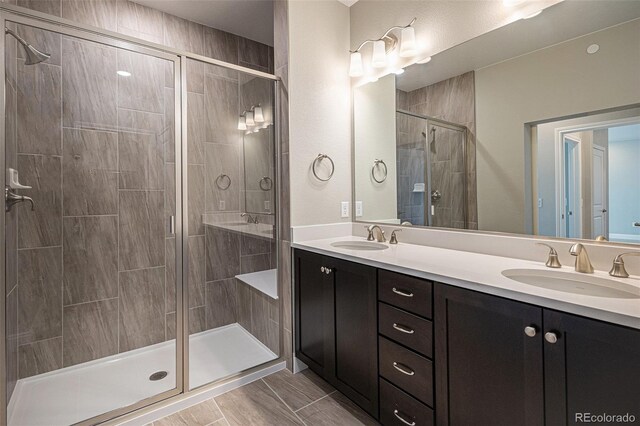 bathroom featuring a shower with shower door and vanity