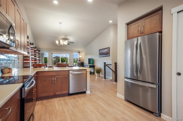 6015 Trappers Tale Ct, Colorado Springs, CO 80923 - kitchen with appliances with stainless steel finishes, vaulted ceiling, a peninsula, a sink, and light wood-style floors