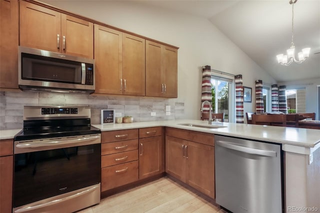 6015 Trappers Tale Ct, Colorado Springs, CO 80923 - kitchen with stainless steel appliances, a sink, a peninsula, vaulted ceiling, and light wood-type flooring
