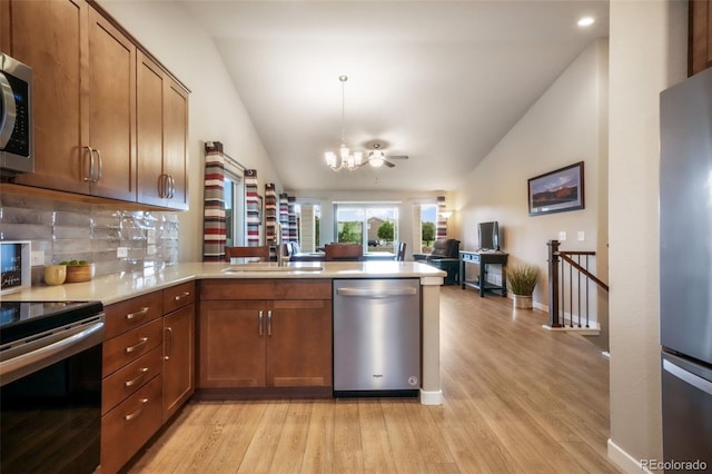 6015 Trappers Tale Ct, Colorado Springs, CO 80923 - kitchen featuring appliances with stainless steel finishes, lofted ceiling, a peninsula, light wood-type flooring, and a chandelier