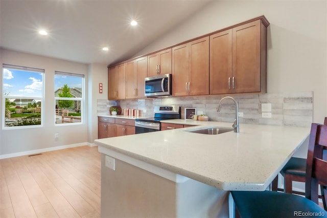 6015 Trappers Tale Ct, Colorado Springs, CO 80923 - kitchen with stainless steel appliances, a sink, light wood-style floors, a breakfast bar, and backsplash