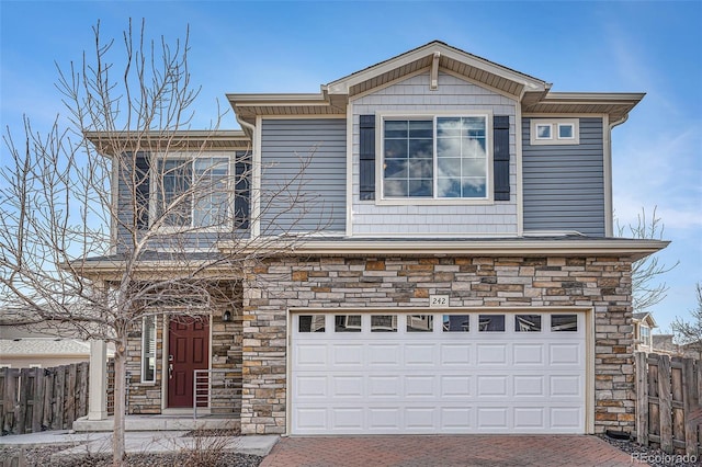 view of front of property featuring an attached garage, stone siding, and fence