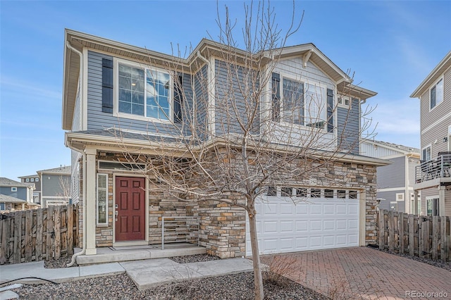 view of front of property with decorative driveway, stone siding, fence, and an attached garage