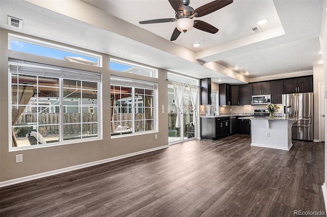 kitchen with dark wood-style floors, a tray ceiling, visible vents, appliances with stainless steel finishes, and baseboards