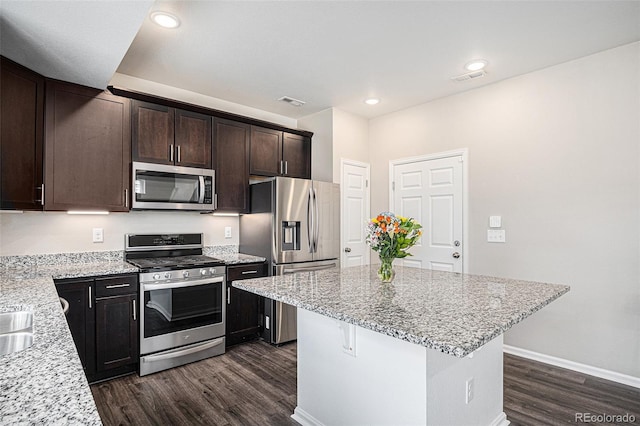 kitchen with stainless steel appliances, light stone counters, and dark wood-style floors