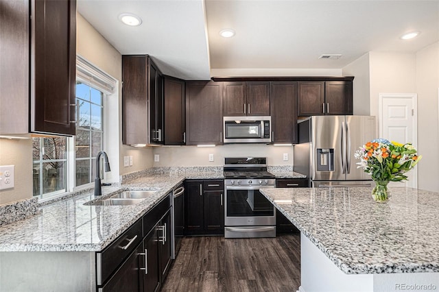 kitchen with visible vents, light stone counters, appliances with stainless steel finishes, dark wood-style flooring, and a sink