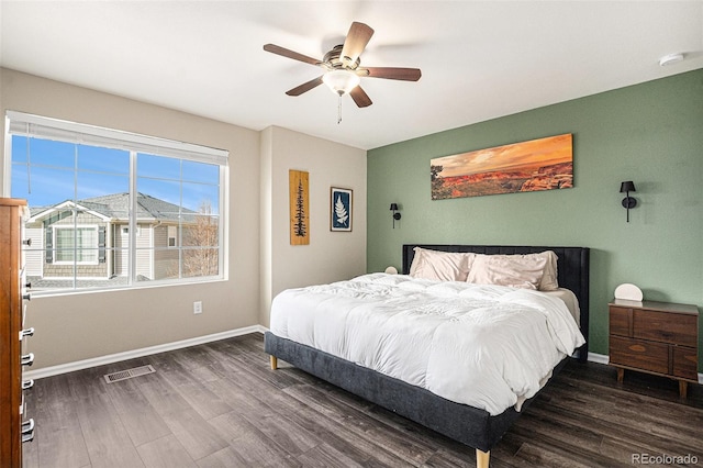 bedroom featuring a ceiling fan, wood finished floors, visible vents, and baseboards