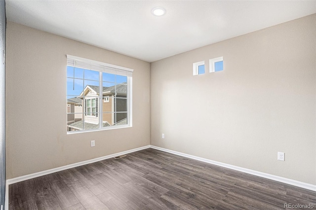 empty room featuring dark wood finished floors, visible vents, and baseboards