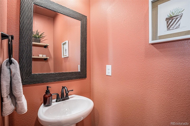 bathroom featuring a textured wall and a sink