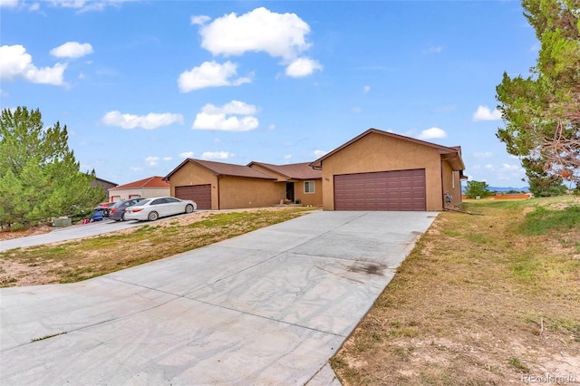 ranch-style house with a garage, driveway, and stucco siding