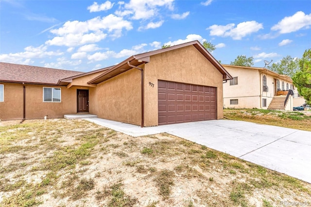 ranch-style home featuring an attached garage, concrete driveway, and stucco siding