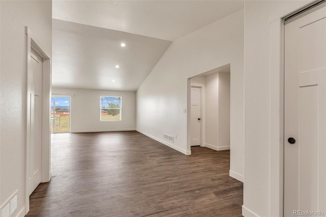 spare room with dark wood-type flooring, lofted ceiling, visible vents, and baseboards