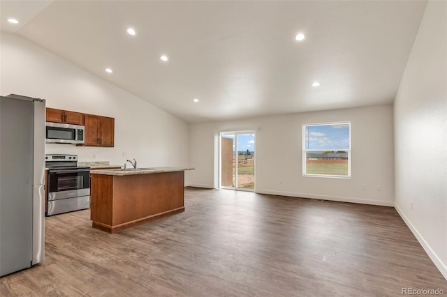 kitchen with a kitchen island with sink, stainless steel appliances, dark wood-type flooring, light countertops, and brown cabinetry