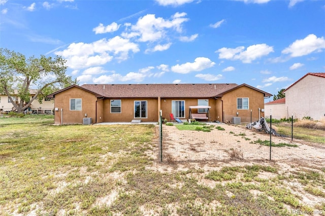 rear view of property with a patio area, central AC, a lawn, and stucco siding