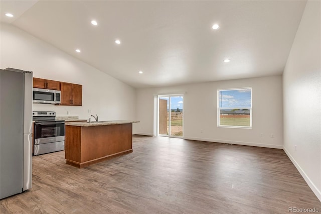 977 S Harmony Dr Unit 979, Pueblo, CO 81007 - kitchen featuring stainless steel appliances, dark wood-type flooring, brown cabinets, lofted ceiling, and an island with sink