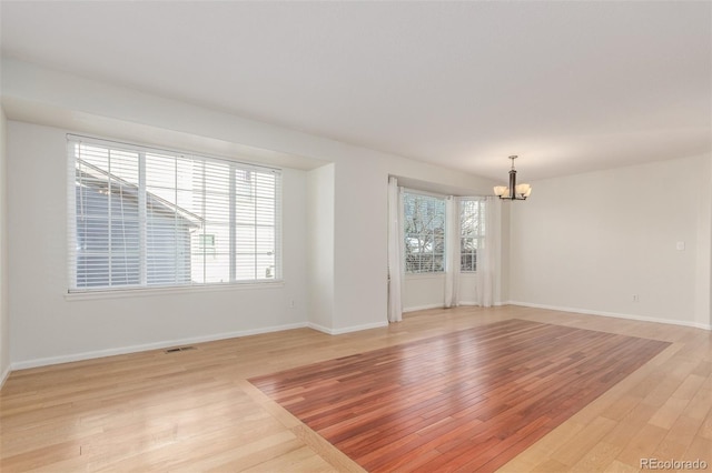 unfurnished room featuring light hardwood / wood-style floors and a chandelier