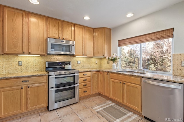 kitchen featuring light stone counters, sink, light tile patterned floors, and appliances with stainless steel finishes