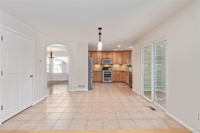 kitchen featuring pendant lighting, appliances with stainless steel finishes, tasteful backsplash, and light tile patterned floors