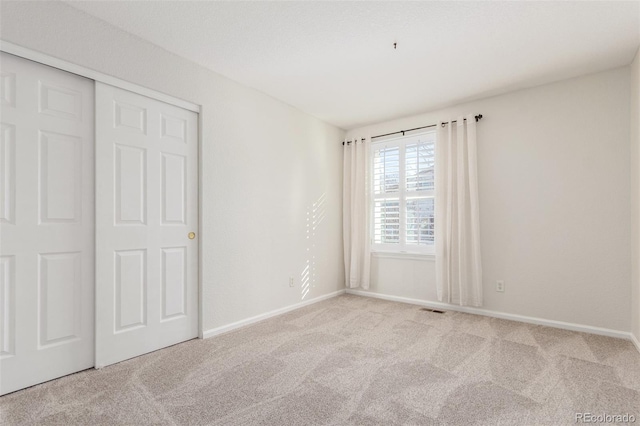 unfurnished bedroom with light carpet and a closet