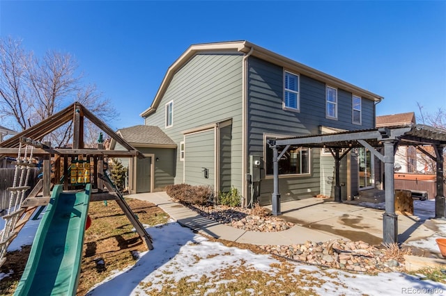 snow covered rear of property with a playground, a patio area, and a pergola