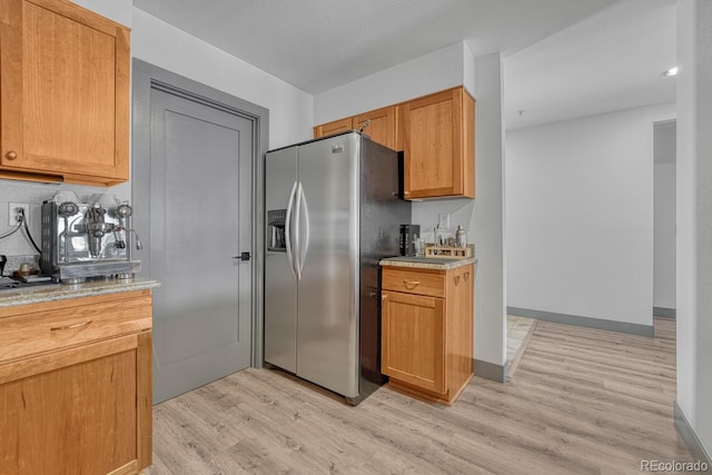 kitchen featuring light wood-type flooring, baseboards, and stainless steel fridge with ice dispenser