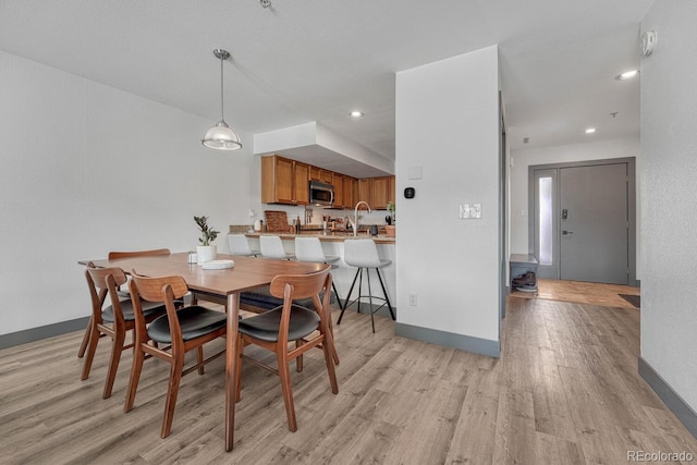 dining room with recessed lighting, baseboards, and light wood-style flooring