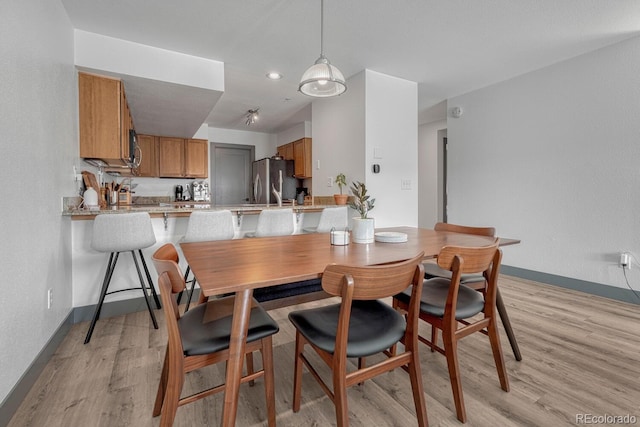 dining area with baseboards and light wood finished floors