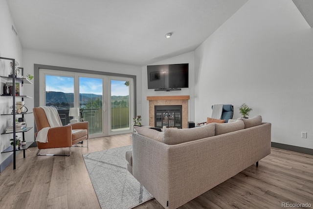 living room featuring baseboards, lofted ceiling, wood finished floors, and a fireplace