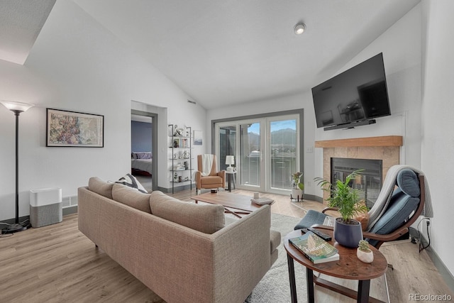 living room featuring visible vents, baseboards, high vaulted ceiling, a fireplace, and light wood-style floors