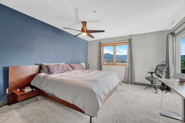carpeted bedroom featuring a mountain view, baseboards, and ceiling fan