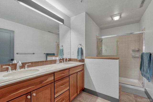 bathroom featuring a sink, a stall shower, and double vanity