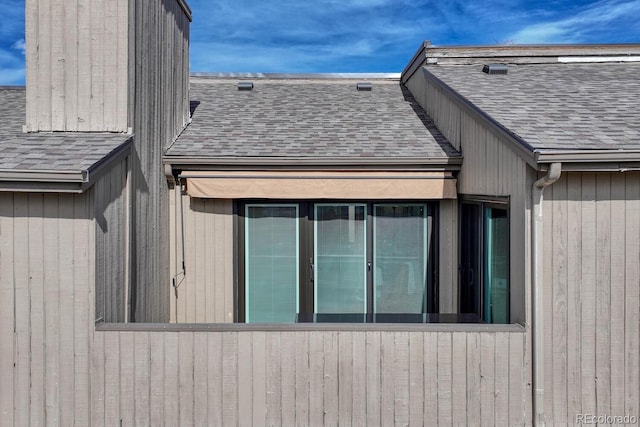 view of side of home with roof with shingles
