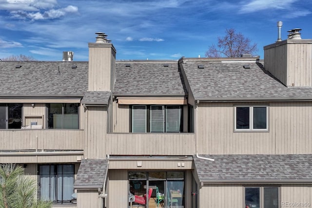 exterior space with roof with shingles and a chimney
