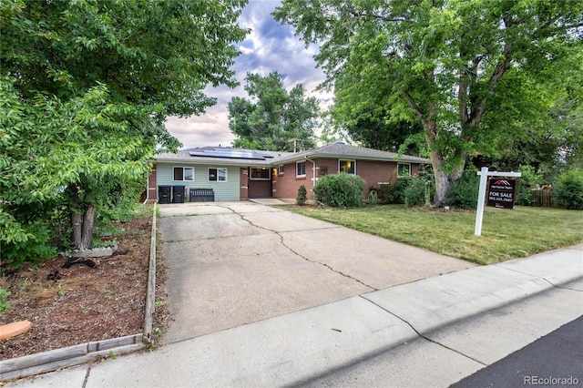 6077 Flower St, Arvada, CO 80004 - ranch-style house with concrete driveway, solar panels, a front yard, and brick siding