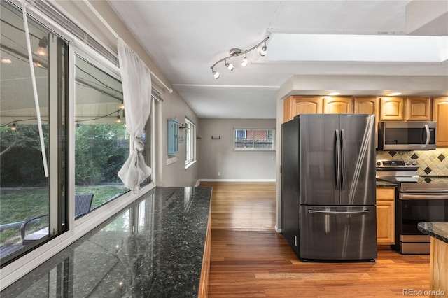 6077 Flower St, Arvada, CO 80004 - kitchen featuring stainless steel appliances, light wood-style flooring, tasteful backsplash, dark stone countertops, and light brown cabinetry