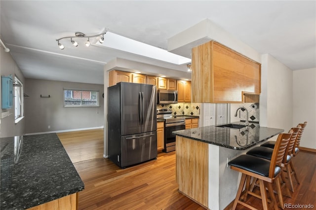6077 Flower St, Arvada, CO 80004 - kitchen with stainless steel appliances, light wood-style flooring, a peninsula, and backsplash
