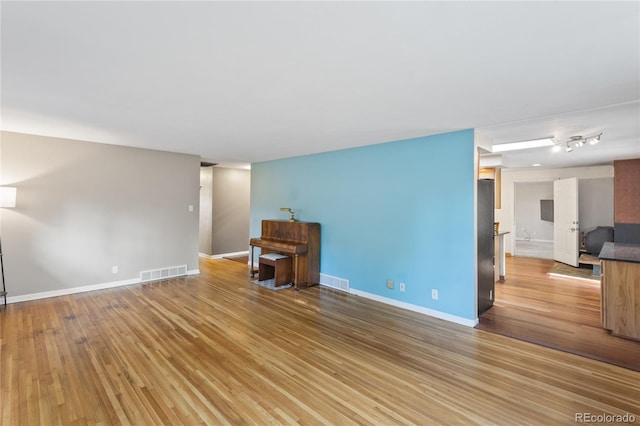 6077 Flower St, Arvada, CO 80004 - unfurnished living room with light wood-style floors and baseboards