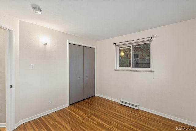 6077 Flower St, Arvada, CO 80004 - unfurnished bedroom with a baseboard heating unit, wood finished floors, and a closet